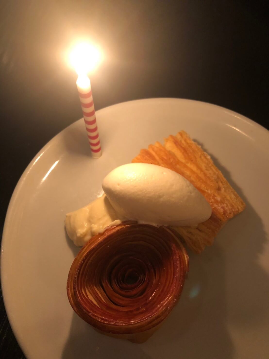 シドニーのレストラン【FRED'S】のデザートメニュー「Roasted apple & buttermink sorbet（ローストアップル＆バターミルクソルベ）」に誕生日を祝うロウソクが灯された様子を撮影した写真